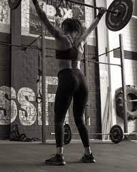 Mujer haciendo ejercicio de push press de crossfit con la barra de halterofilia